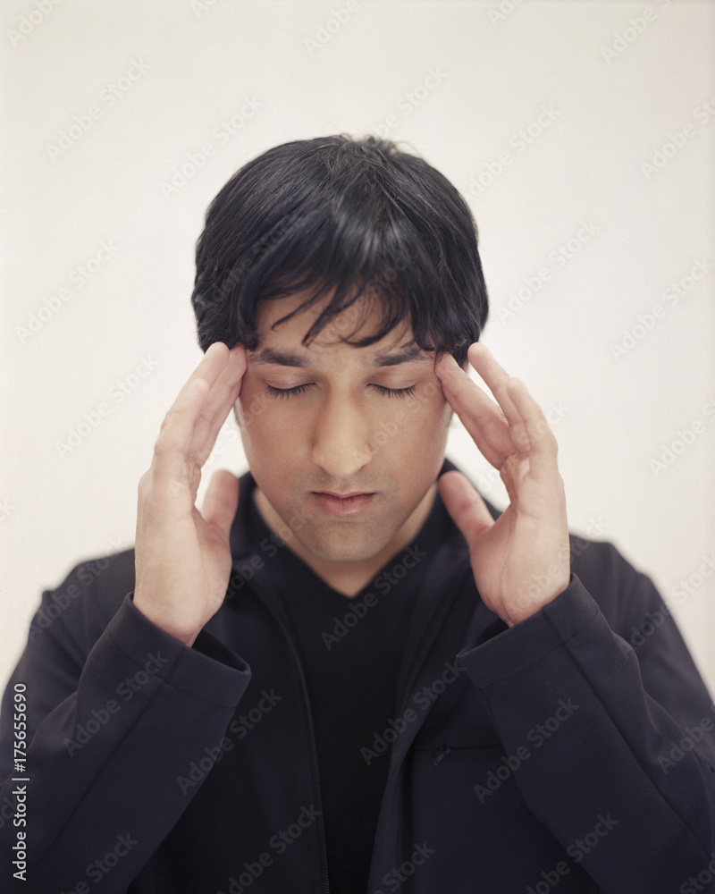 Portrait of handsome young man with eyes closed and hands to head Portrait of handsome young man with eyes closed and hands to head