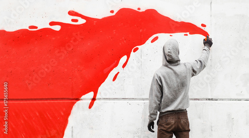 Street artist drawing with spraycan on wall