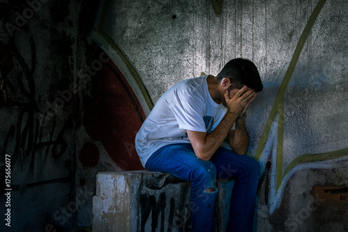 Joven cubriéndose la cara en casa abandonada, triste, 