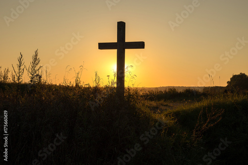 Wooden cross in the rural area against the background of a sunset in the summer © marcenko
