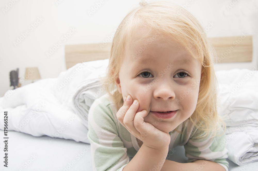 little girl hiding in bed under a white blanket or a blanket. Child in bed