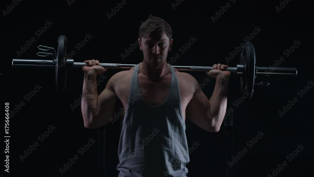 Muscular man weight training, doing squats with barbell Muscular man weight training, doing squats with barbell