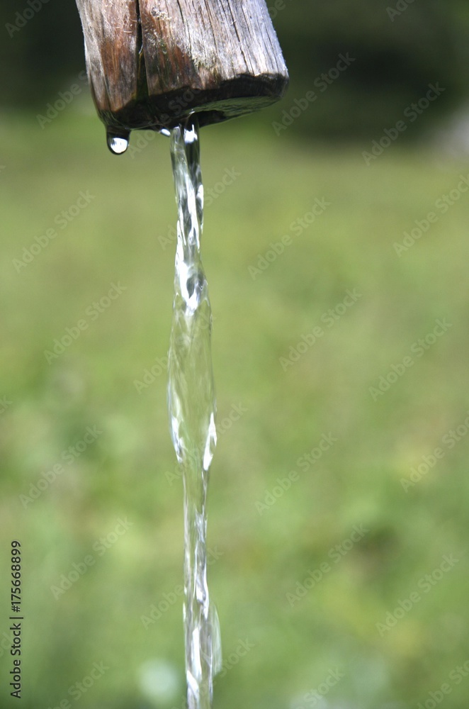 Stream of water flowing from a wooden fountain, well Stream of water flowing from a wooden fountain, well