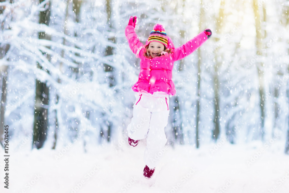 Child playing with snow in winter. Kids outdoors.