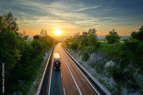 Obraz na płótnie Truck driving on the highway in a rural landscape at sunset. View from above. w salonie