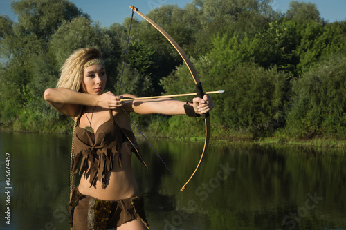 Wild amazon girl shoots from the bow. photo