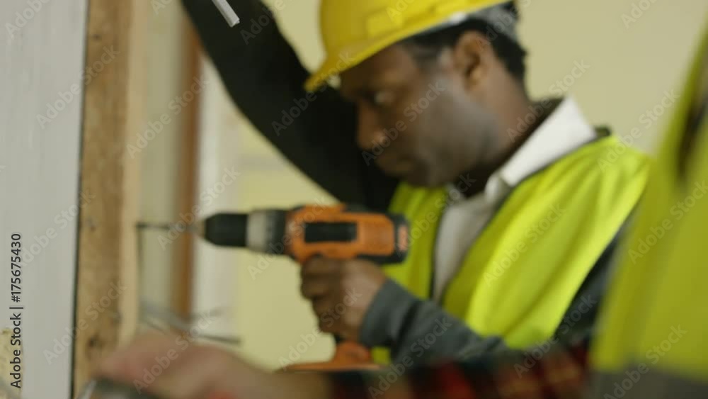 Construction workers on a building site drilling & checking wiring Construction workers on a building site drilling & checking wiring