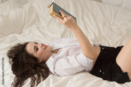 girl is reading a book in bed
