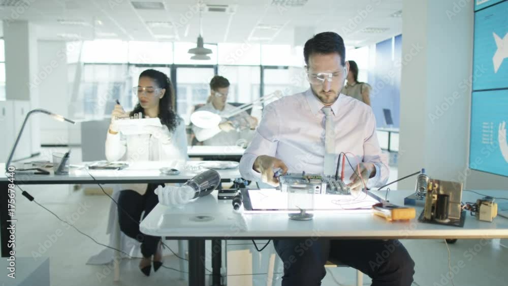 Electronics engineers working in lab with man building circuit board Electronics engineers working in lab with man building circuit board