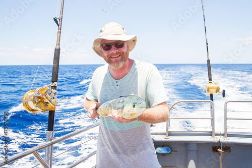 Man holding fresh caught Mahi Mahi on ocean boat
