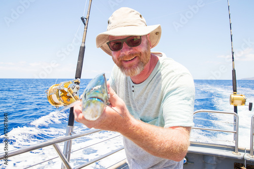 Man holding fresh caught Mahi Mahi on ocean boat