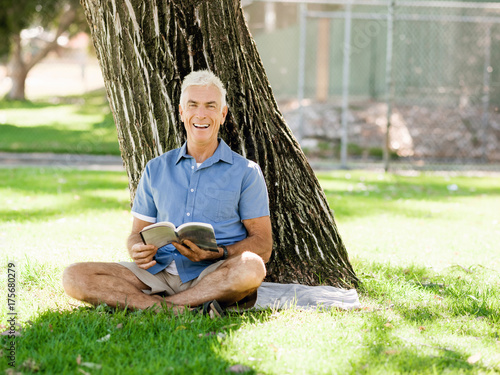 Senior man sittingin park while reading book photo