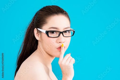Young Asian woman with secret hush pose isolated on blue background.