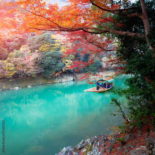 Boatman punting the boat for tourists to enjoy the autumn view, The katsura river in the morning, Kyoto Japan