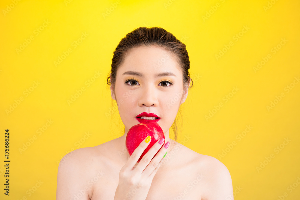Young Asian woman eating apple isolated in yellow background Young Asian woman eating apple isolated in yellow background