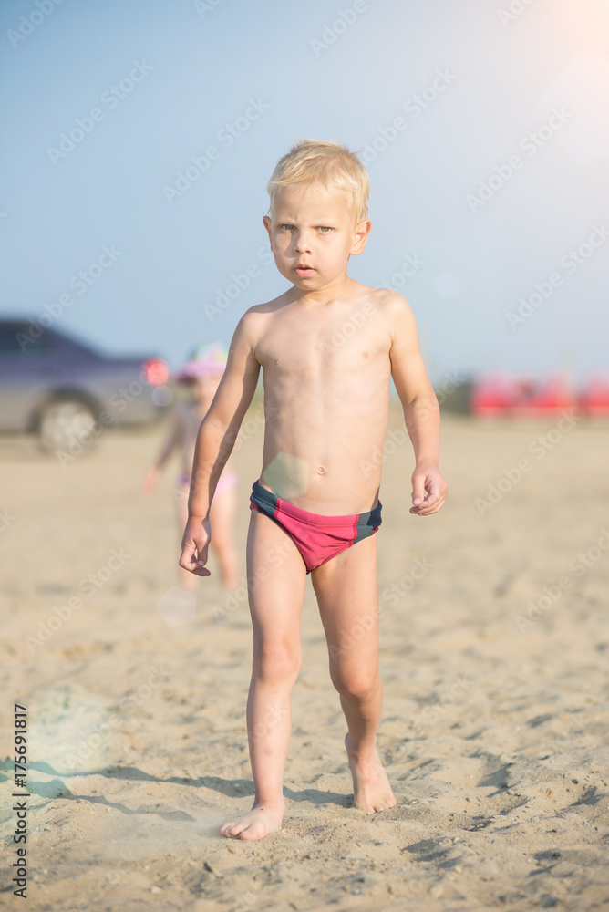 Baby boy walking on the sandy beach near the sea. Cute little kid at sand tropical beach. Ocean coast. Baby boy walking on the sandy beach near the sea. Cute little kid at sand tropical beach. Ocean coast.