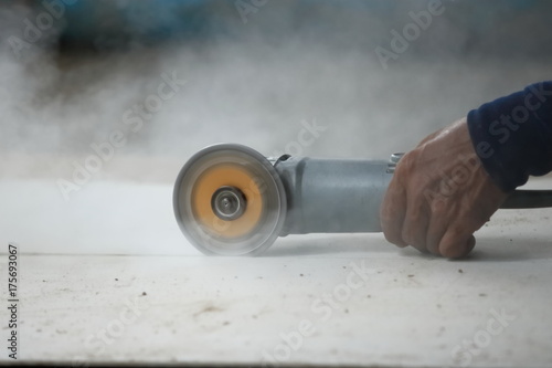 Selective focus on angle grinder cutting concrete.