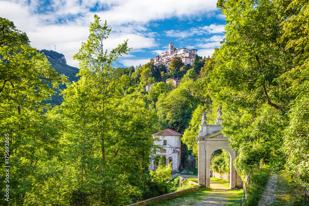 Sacro Monte of Varese (Santa Maria del Monte), Italy. Via Sacra that leads to medieval village (in the background), with the tenth chapel and the third arc. World Heritage Site - Unesco - obrazy, fototapety, plakaty 