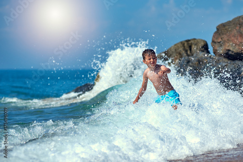 Cute Caucasian boy in sea waves. © Artem
