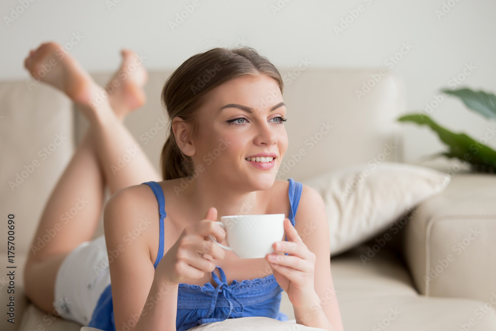 Dreamy young thoughtful woman relaxing on comfortable sofa at home, enjoying cup of coffee in the morning, happy relaxed girl resting on cozy couch, starting new day with positive thoughts, portrait Dreamy young thoughtful woman relaxing on comfortable sofa at home, enjoying cup of coffee in the morning, happy relaxed girl resting on cozy couch, starting new day with positive thoughts, portrait