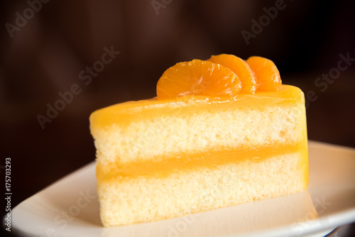 Orange cake on plate with blur brown background