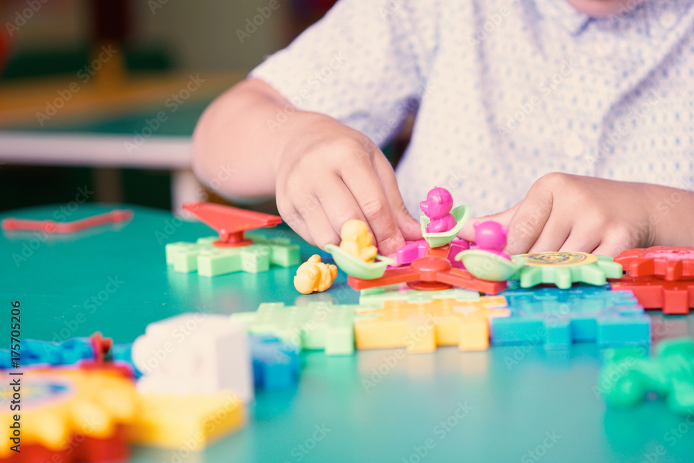 Little boy's hands playing with colorful plastic bricks at the table. Kids having fun and building out of bright constructor bricks. Early learning. Developing toys Little boy's hands playing with colorful plastic bricks at the table. Kids having fun and building out of bright constructor bricks. Early learning. Developing toys