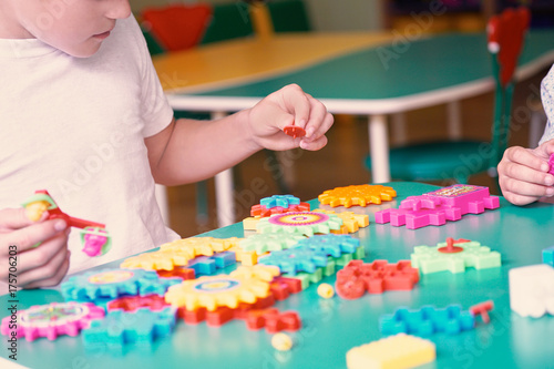 Little boys playing with colorful plastic bricks at the table. Kids having fun and building out of bright constructor bricks. Early learning. Developing toys