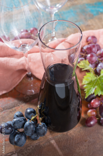 Small carafe with dry red wine, two wine glasses and grapes photo