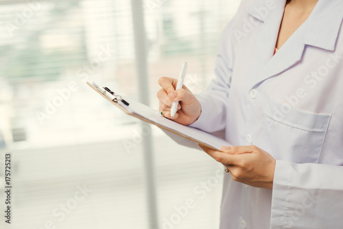Soft focus asian medical female doctor or nurse holding patient medical chart.