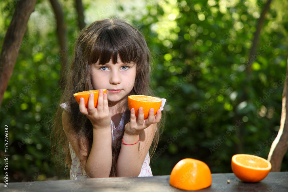 Girl and oranges. Girl playing with oranges at a table in nature. Child with oranges. Happy girl with fruits on nature. Healthy lifestyle. Girl and oranges. Girl playing with oranges at a table in nature. Child with oranges. Happy girl with fruits on nature. Healthy lifestyle.