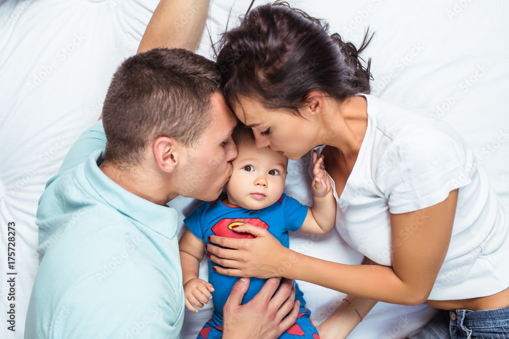 Mother and father enjoying and relaxing with their baby on bed.