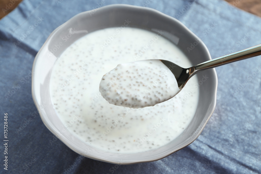 Spoon with delicious chia seed pudding over bowl on table Spoon with delicious chia seed pudding over bowl on table