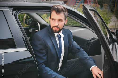Handsome man in suit getting out of car © Africa Studio