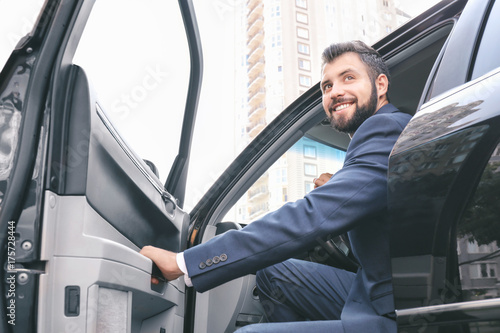 Handsome man in suit getting out of car