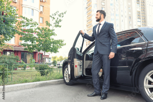 Handsome young man in elegant suit standing near car outdoors © Africa Studio
