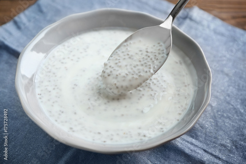 Spoon and bowl with delicious chia seed pudding on table