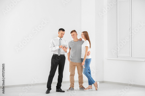 Happy family and estate agent with tablet in light new apartment