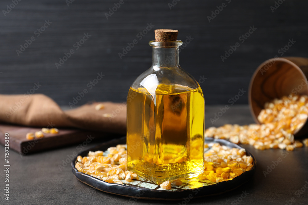Glass bottle with corn oil and dried kernels on dark background Glass bottle with corn oil and dried kernels on dark background