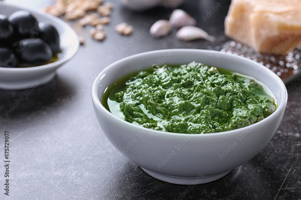 Bowl with delicious basil pesto sauce on table