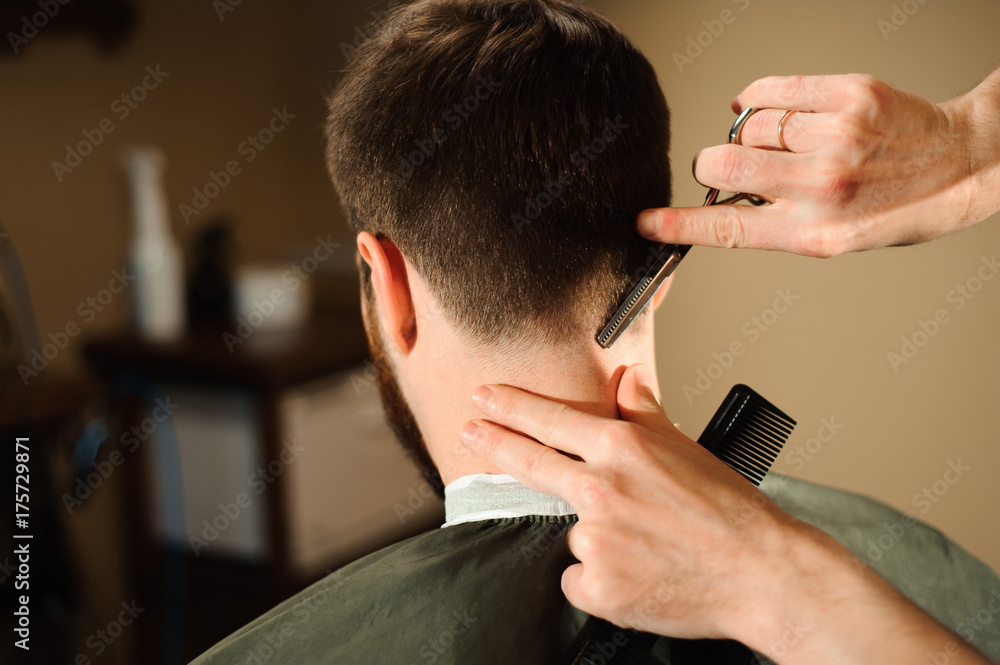 Fototapeta premium Master cuts hair and beard of men in the barbershop