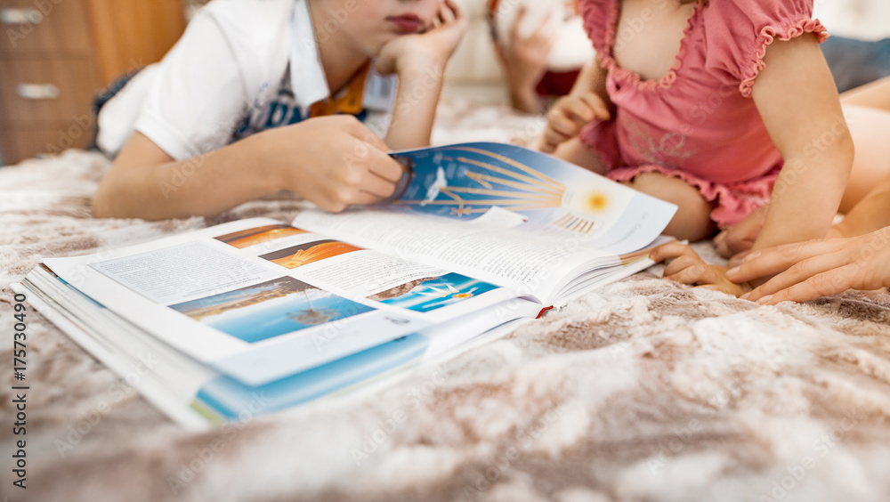 The elder brother and younger sister read the encyclopedia on the bed in the apartment The elder brother and younger sister read the encyclopedia on the bed in the apartment