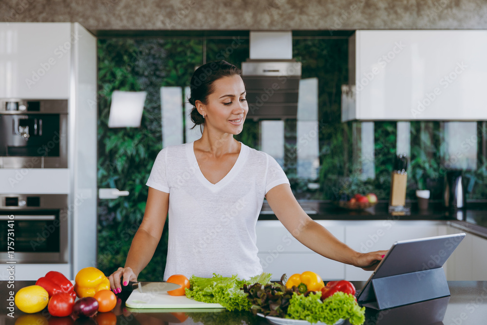 Young woman looking at recipe in laptop in kitchen. Healthy food - Vegetable salad. Diet. Dieting concept. Healthy lifestyle. Cooking at home. Prepare food. With place for text. Young woman looking at recipe in laptop in kitchen. Healthy food - Vegetable salad. Diet. Dieting concept. Healthy lifestyle. Cooking at home. Prepare food. With place for text.