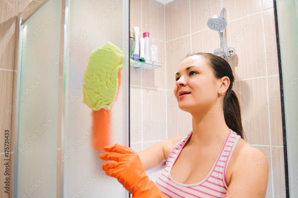 portrait of young woman cleaning shower door portrait of young woman cleaning shower door