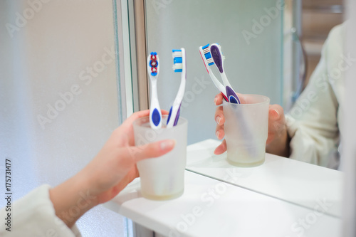 Image of pretty female brushing her teeth in front of mirror in the morning © nagaets