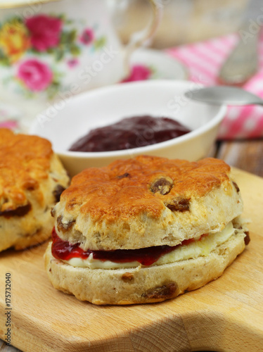 Traditional raisin scone with strawberry jam and fresh clotted cream, closeup 