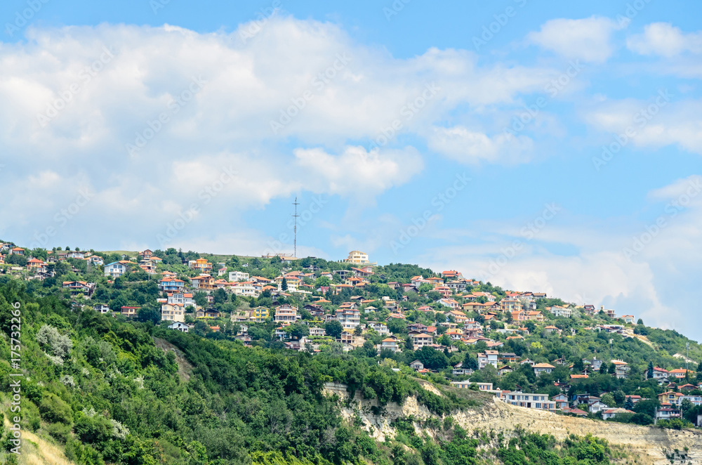 The Black Sea shore, green hills with houses, blue clouds sky. City Balchik coast