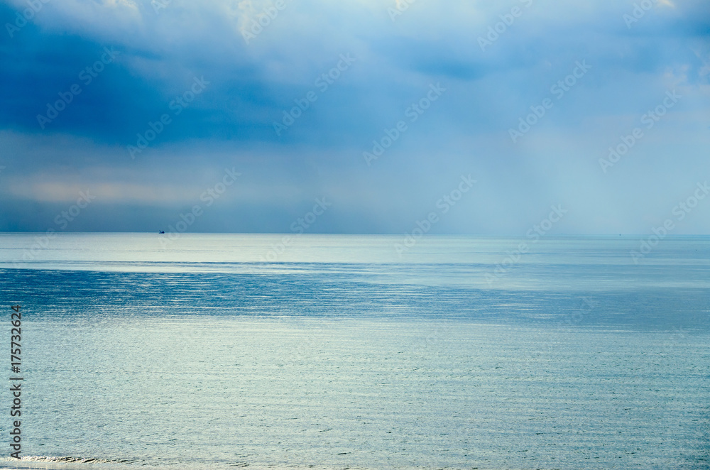 The Black Sea shore with  blue fresh clear water, mystical clouds sky