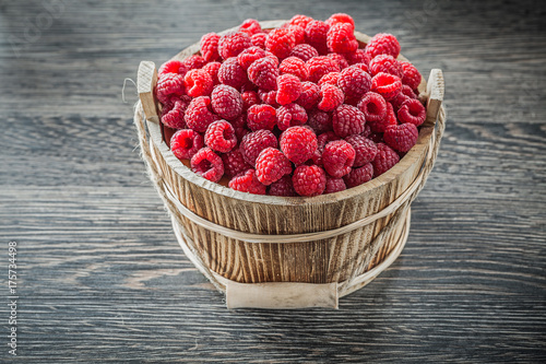 Raspberries in bucket on wooden board