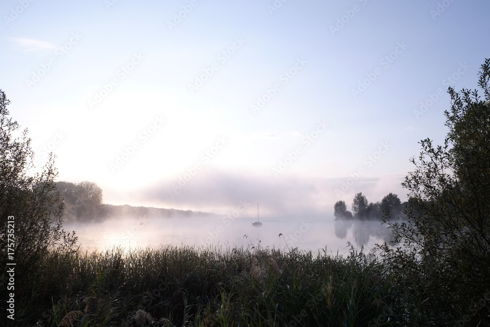 Morning mist over lake with sailboat - 1