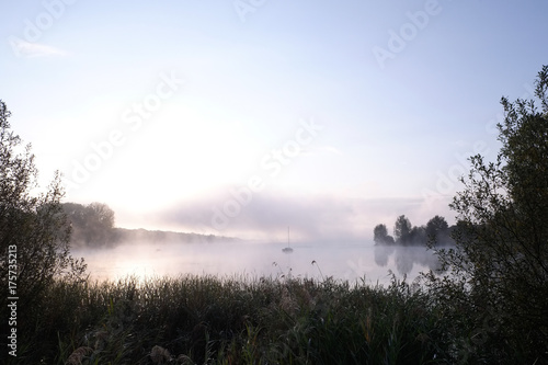 Morning mist over lake with sailboat - 1